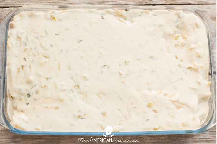 creamy sauce poured over Green Chile Spinach chicken enchiladas before baking